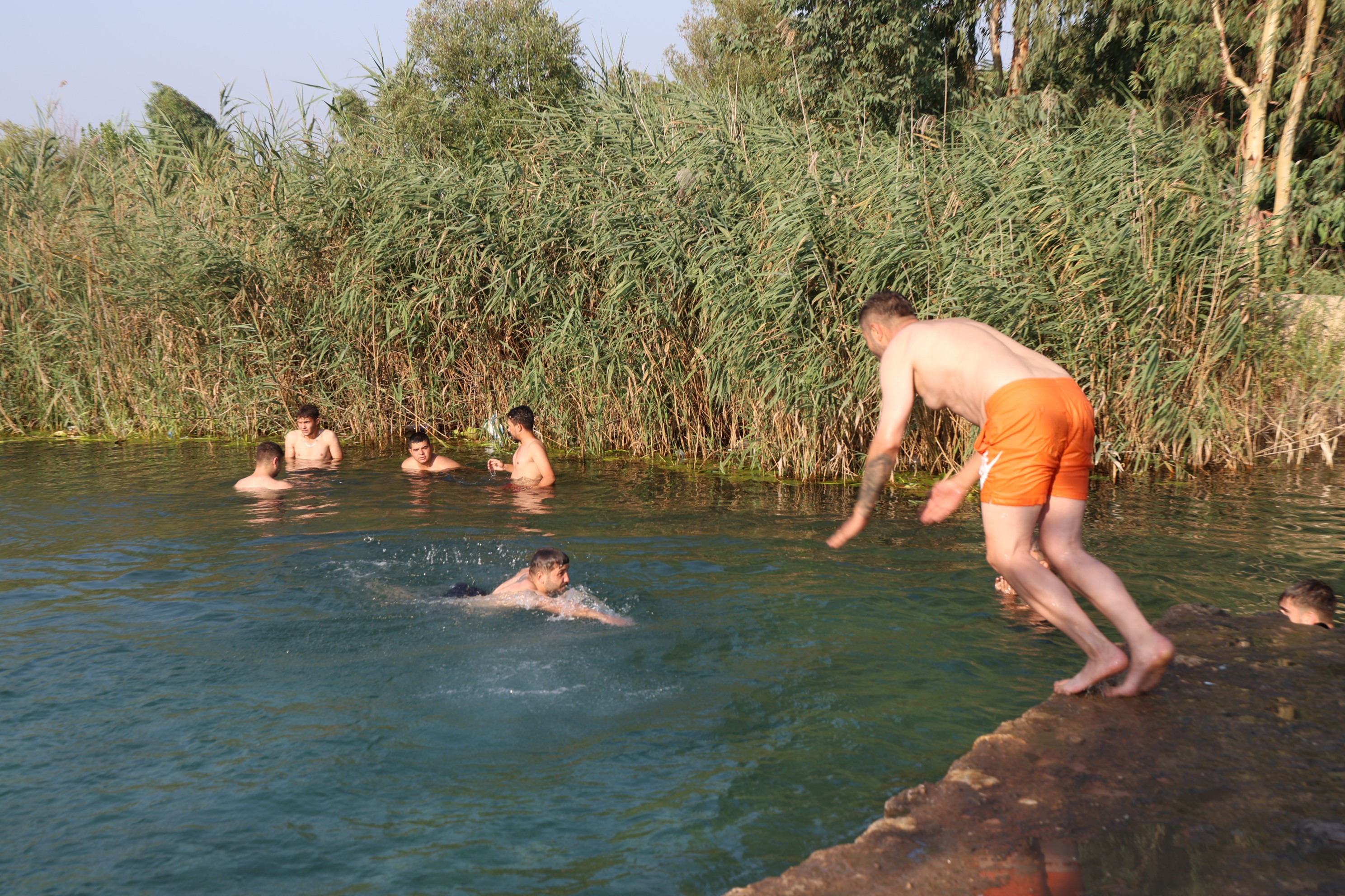 Adana'da gençler bunaltan sıcakta gölette serinledi