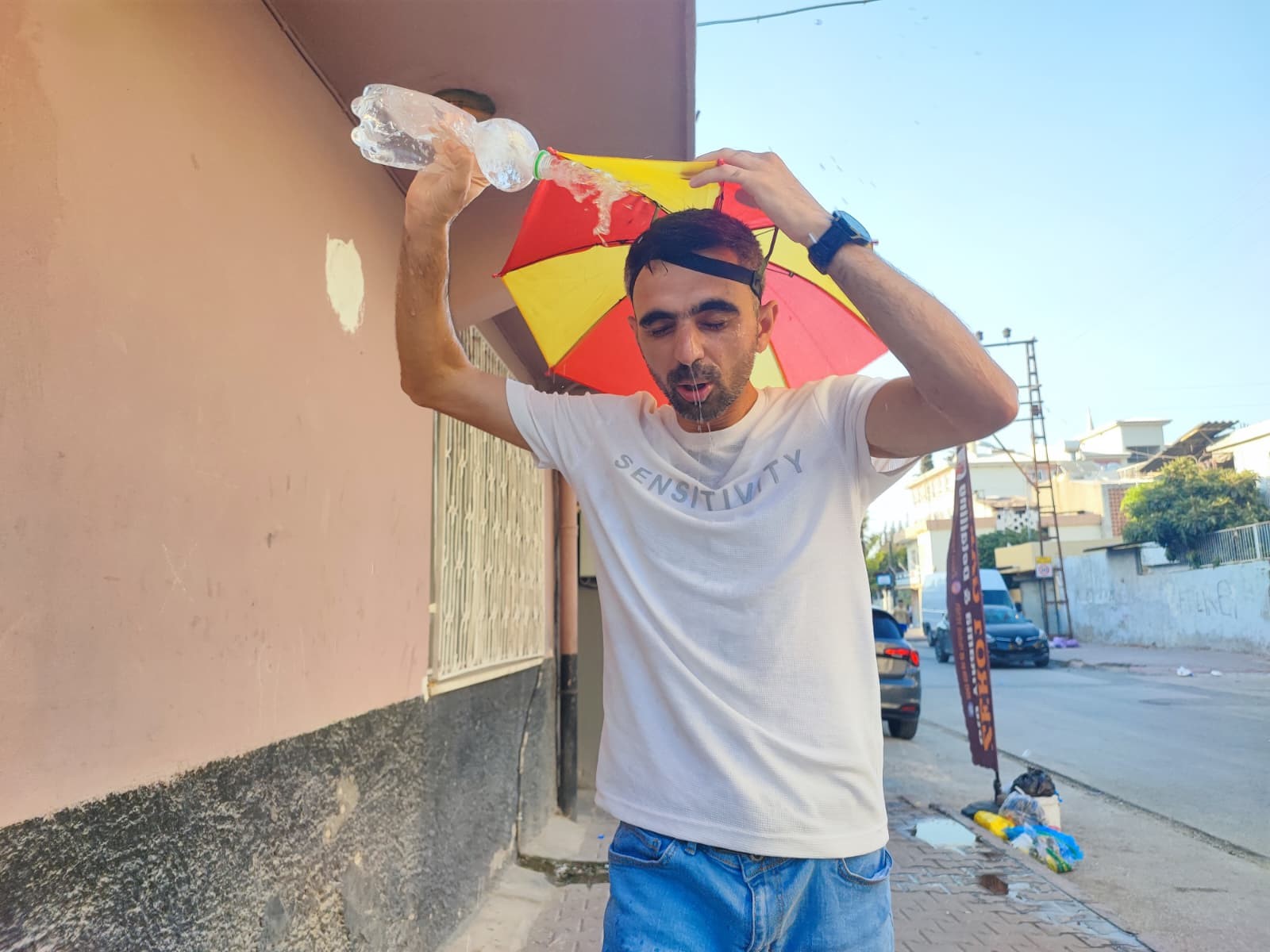 Aşırı sıcaklar nedeniyle kafasına taktığı şemsiye ile geziyor