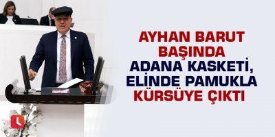 Ayhan Barut başında Adana kasketi, elinde pamukla kürsüye çıktı