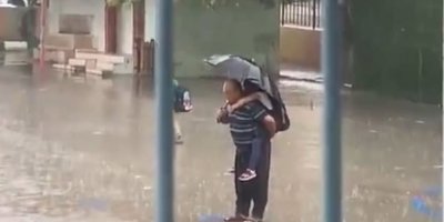 Dede torununu sırtına alarak yağmur altında İstiklal Marşı okudu