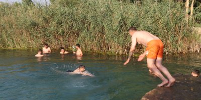 Adana'da gençler bunaltan sıcakta gölette serinledi