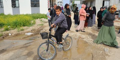 Adana'da altyapı ve yol sorunu yaşandığı belirtilen mahallede bir anne, engelli evladıyla eylem yaptı